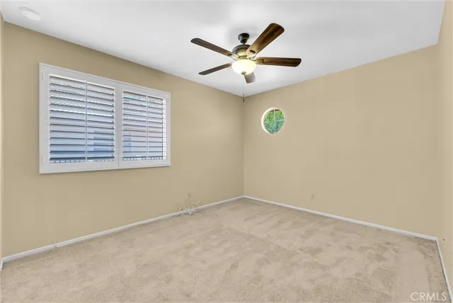 an empty room with a window and a ceiling fan