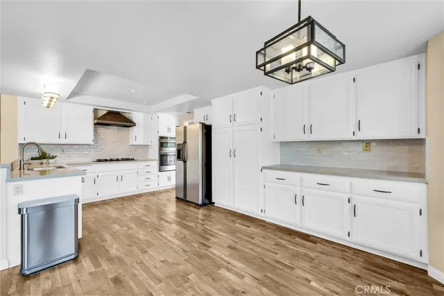 a kitchen with stainless steel appliances white cabinets and a chandelier