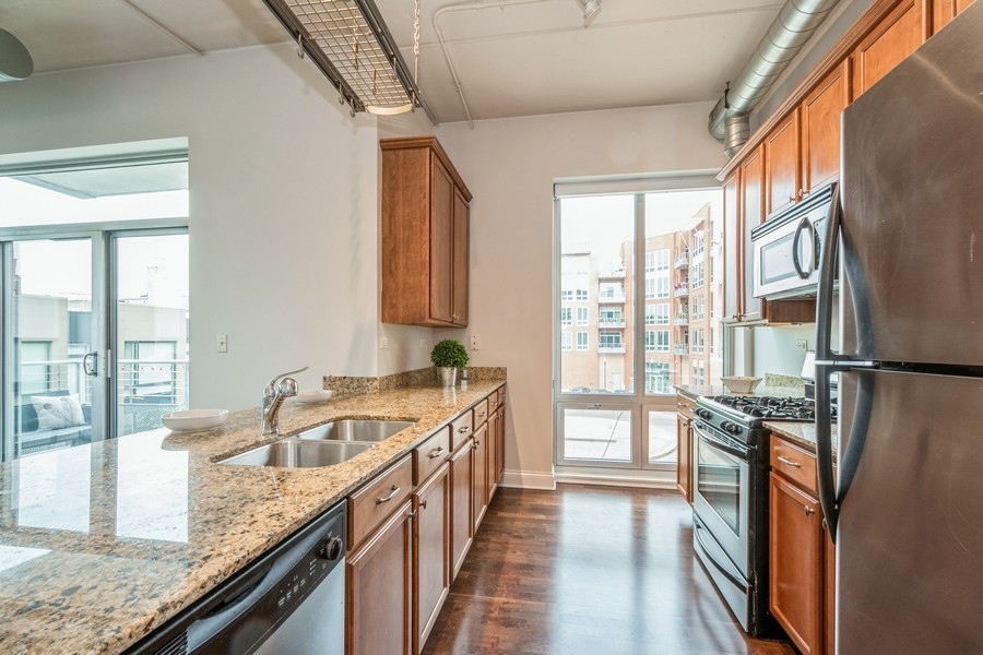 4814 North Clark Street, Unit 201 Chicago, IL 60640 - Photo 11 of 24 a kitchen with granite countertop a sink a counter top space and stainless steel appliances