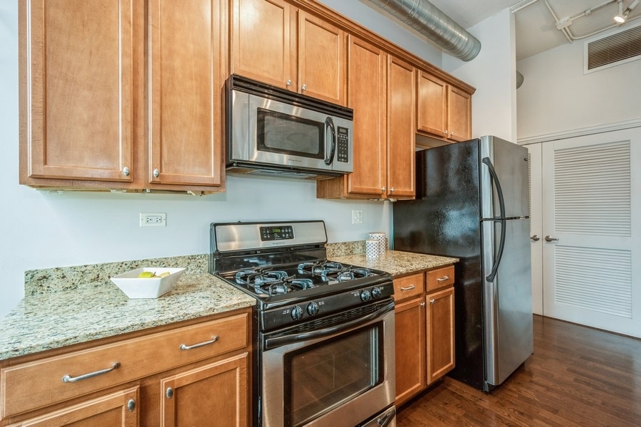 4814 North Clark Street, Unit 201 Chicago, IL 60640 - Photo 12 of 24 a kitchen with stainless steel appliances granite countertop a stove microwave refrigerator and sink