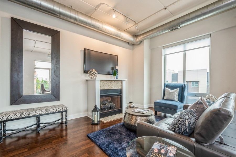 4814 North Clark Street, Unit 201 Chicago, IL 60640 - Photo 4 of 24 a living room with furniture a flat screen tv and a fireplace