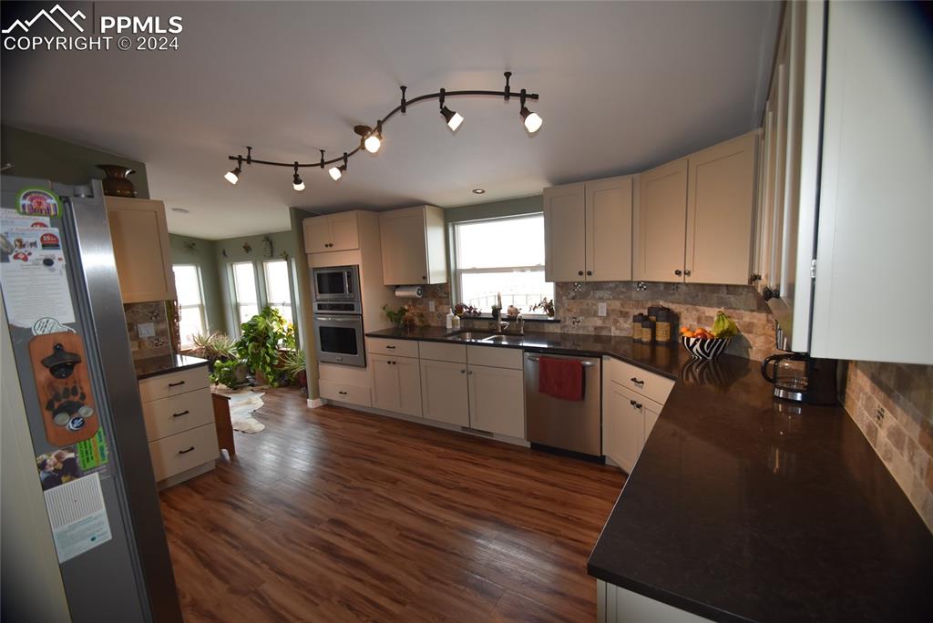 9990 Hahn Road Calhan, CO 80808 - Photo 3 of 25 a kitchen with granite countertop a refrigerator a stove top oven a sink dishwasher and white cabinets with wooden floor