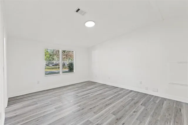 an empty room with wooden floor and windows