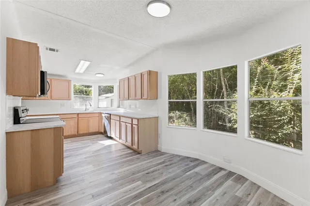 a kitchen with stainless steel appliances wooden floors and large window