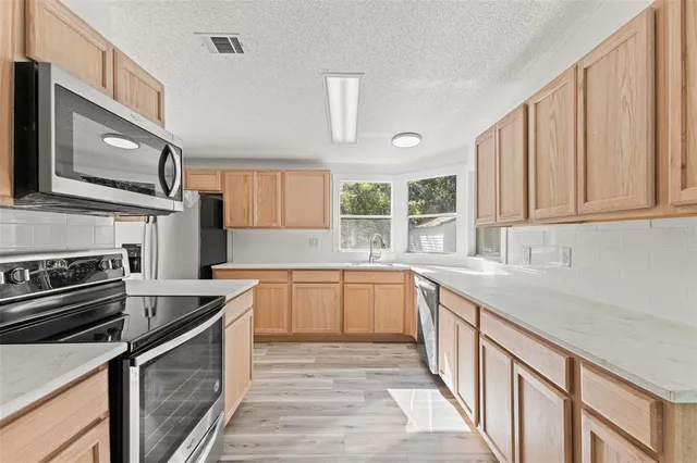 a kitchen with stainless steel appliances granite countertop a stove sink and cabinets