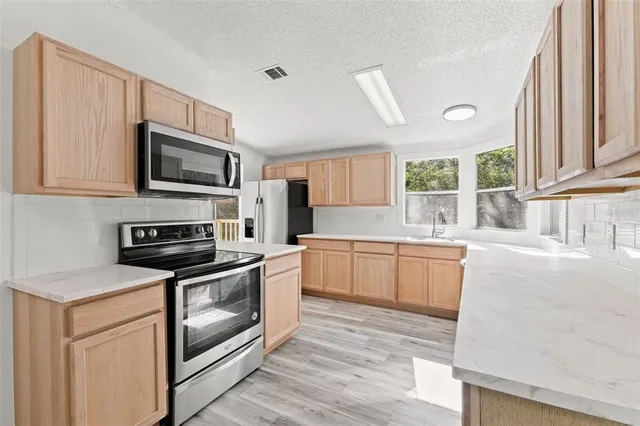 a kitchen with stainless steel appliances white cabinets a stove a sink and a microwave