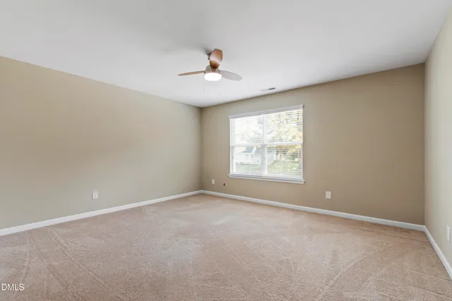 an empty room with a window and ceiling fan