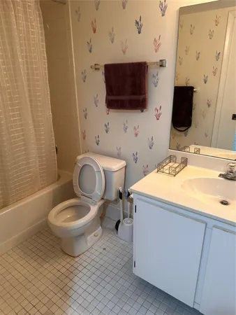 a bathroom with a sink toilet a mirror and shower curtain