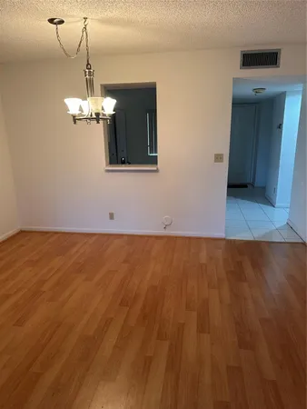 a view of a room with wooden floor and chandelier