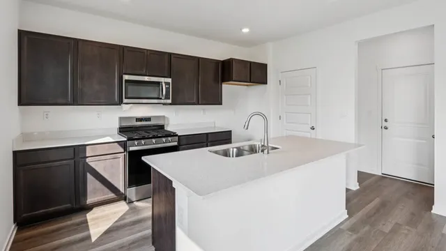 a kitchen with stainless steel appliances a sink a stove top oven a counter space and cabinets