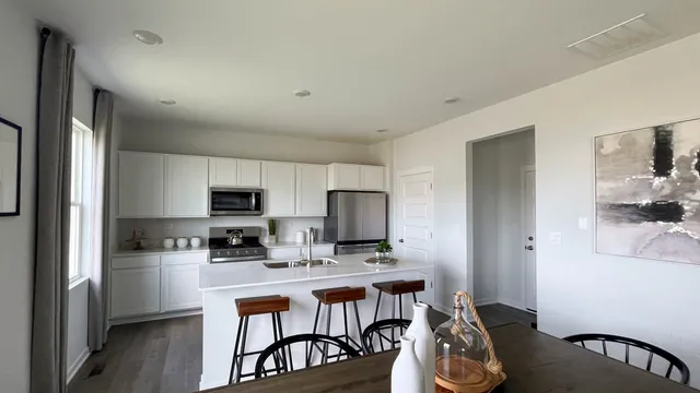 a kitchen with stainless steel appliances a microwave a stove a refrigerator a sink a stove and white cabinets