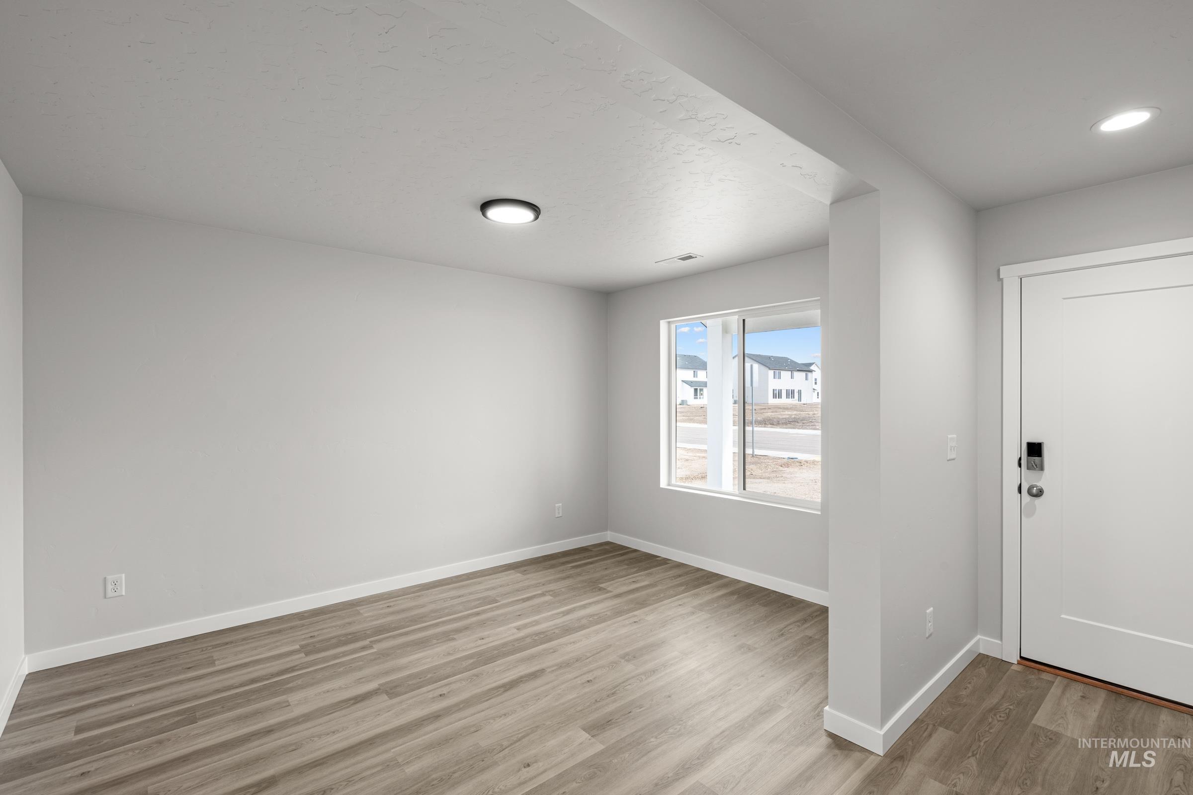 14056 Shiny Spruce Street Caldwell, ID 83607 - Photo 10 of 25 Spacious interior featuring wood-finish flooring, white baseboards, and light gray walls