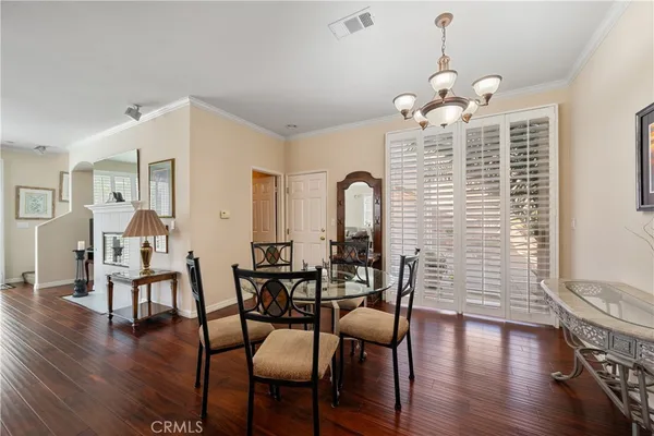a dining room with wooden floor a chandelier a wooden table and chairs