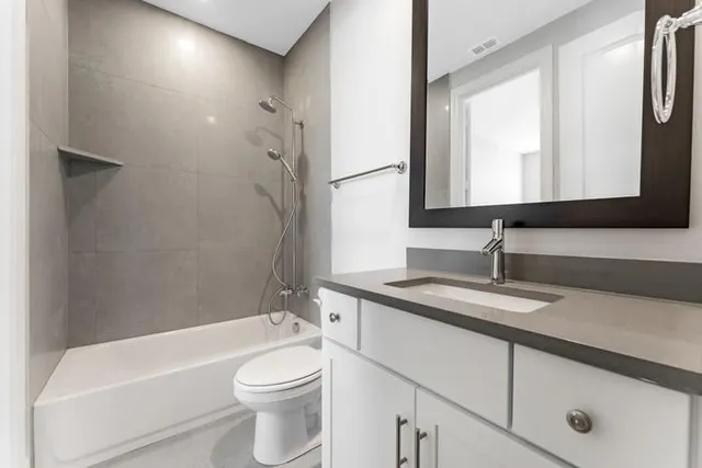 a bathroom with a granite countertop sink toilet mirror and bathtub