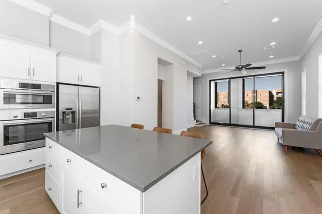 a kitchen with stainless steel appliances granite countertop a refrigerator a stove and a wooden floors