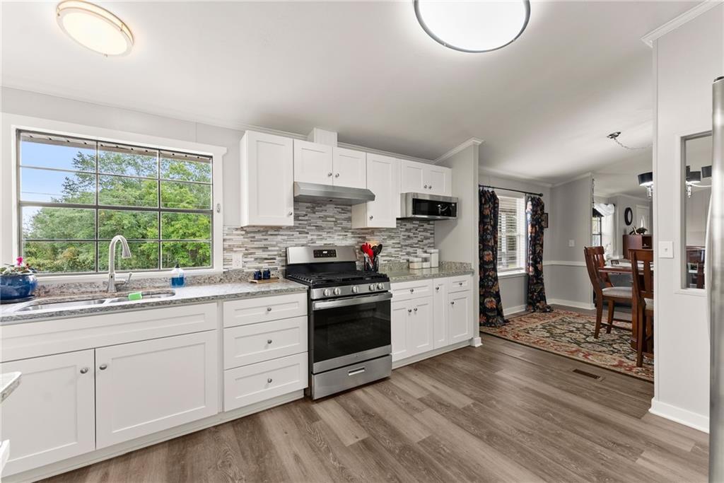 1689 Old State Road Pendergrass, GA 30567 - Photo 26 of 58 a kitchen with stainless steel appliances granite countertop a stove a sink dishwasher and a refrigerator with wooden floors