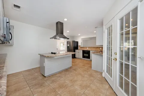a living room with stainless steel appliances kitchen island granite countertop a refrigerator and a sink