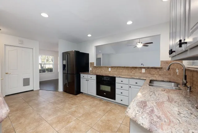 a large kitchen with granite countertop a refrigerator and a stove top oven