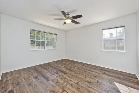 a view of empty room with wooden floor and fan
