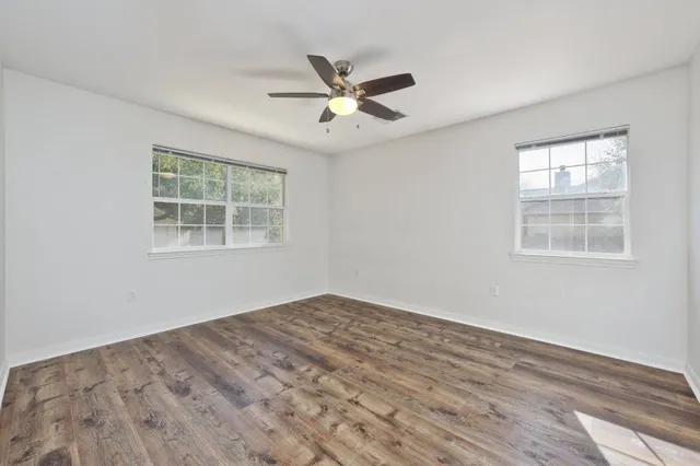 a view of empty room with wooden floor and fan
