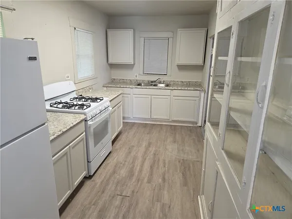 a kitchen with white cabinets and white appliances