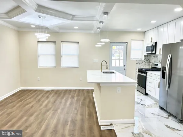 a kitchen with stainless steel appliances a sink a stove a refrigerator cabinets and a dining table