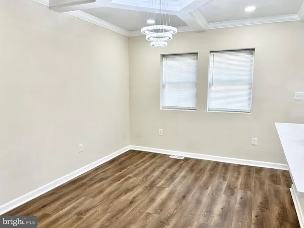 an empty room with a chandelier fan and windows