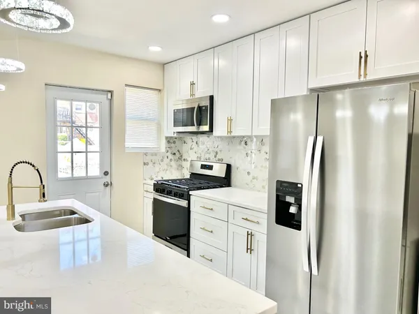 a kitchen with stainless steel appliances granite countertop a refrigerator a sink a stove a microwave and island