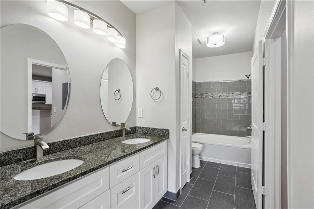 821 Ralph McGill Boulevard Northeast, Unit 2113 Atlanta, GA 30306 - Photo 6 of 29 a bathroom with a granite countertop sink mirror toilet and bathtub