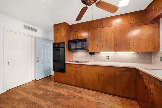 a kitchen with stainless steel appliances kitchen island granite countertop a refrigerator a sink dishwasher a stove and a refrigerator with wooden floor