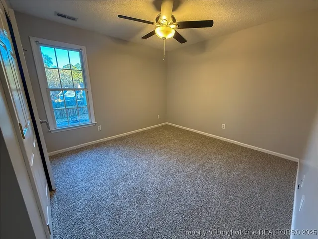 an empty room with windows and fan