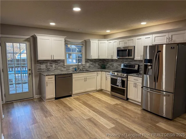 a kitchen with stainless steel appliances granite countertop a stove top oven a refrigerator a sink and a microwave
