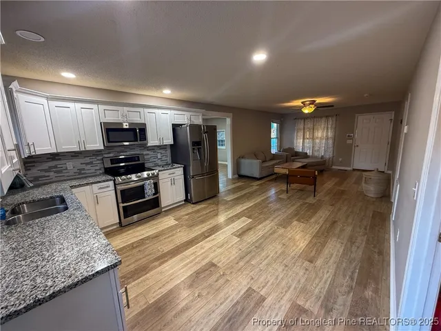 a kitchen with stainless steel appliances granite countertop a sink stove and refrigerator
