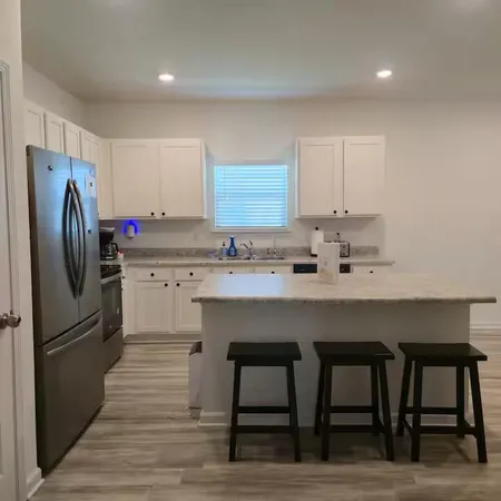a kitchen with stainless steel appliances a table chairs refrigerator and sink