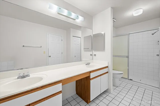 a spacious bathroom with a double vanity sink toilet and a mirror