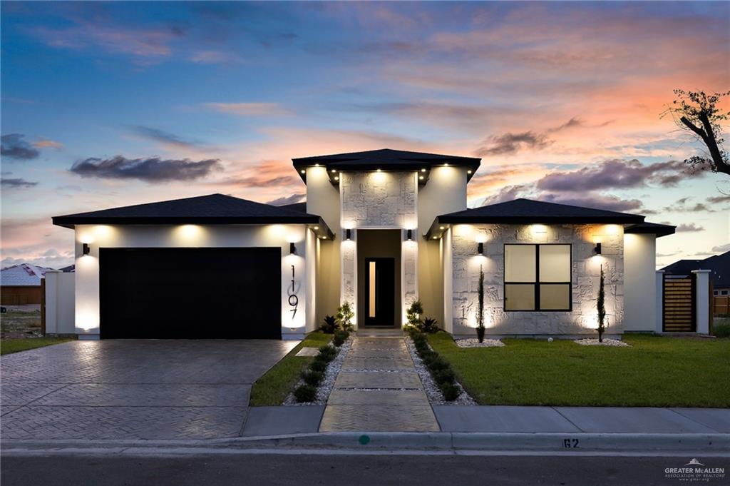 1107 Benjamin Street Mission, TX 78573 - Photo 1 of 19 Modern exterior featuring a prominent black garage door, integrated exterior lighting, a textured stone facade, a contemporary entryway, and a manicured lawn