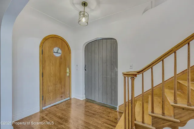 a view of a hallway with wooden floor and stairs