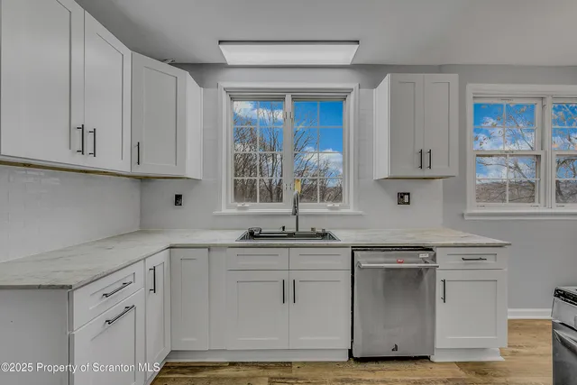 a kitchen with stainless steel appliances granite countertop a sink and cabinets with wooden floor