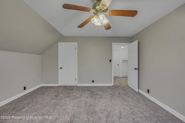 a view of an empty room with chandelier fan and a window