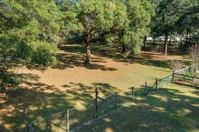 an aerial view of residential house with outdoor space and trees all around