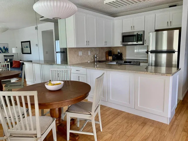 a kitchen with stainless steel appliances granite countertop a kitchen island a white cabinets a sink and a refrigerator