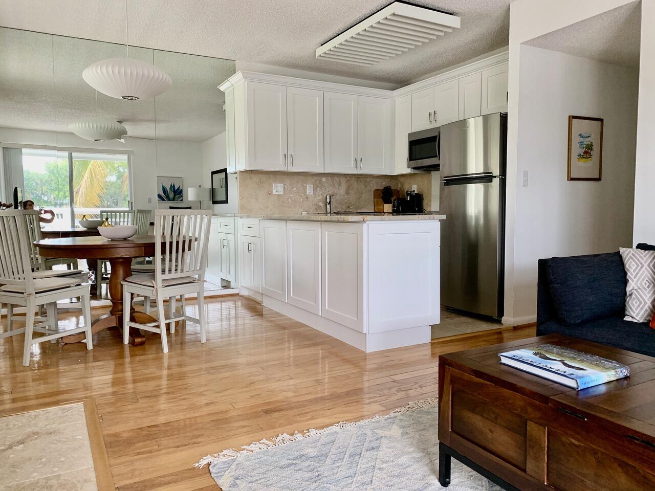 353 Highway 1, Unit C7 Jupiter, FL 33477 - Photo 7 of 25 a kitchen with stainless steel appliances kitchen island granite countertop a refrigerator a stove a microwave oven with white cabinets and wooden floor