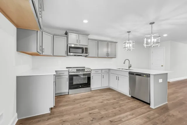 a kitchen with kitchen island granite countertop a stove top oven a sink a counter space and cabinets