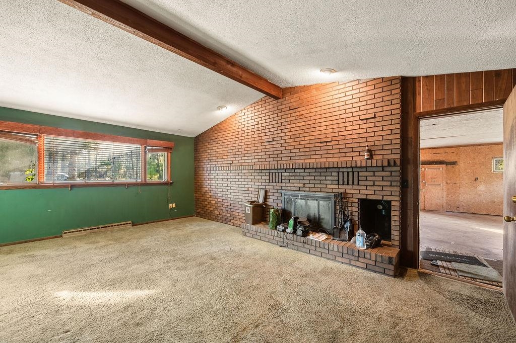 1421 Janis Road Cloquet, MN 55720 - Photo 9 of 52 Unfurnished living room featuring brick wall, a fireplace, carpet flooring, a textured ceiling, and a baseboard heating unit