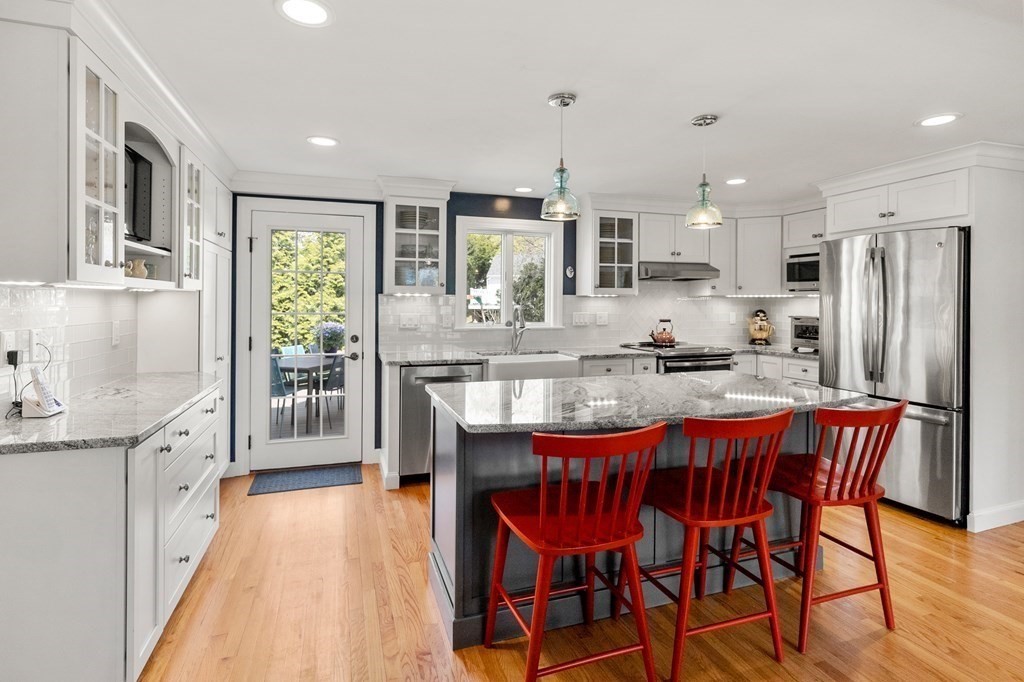 26 Cherokee Road Arlington, MA 02474 - Photo 8 of 40 a kitchen with stainless steel appliances granite countertop a stove a refrigerator a kitchen island and chairs with wooden floor