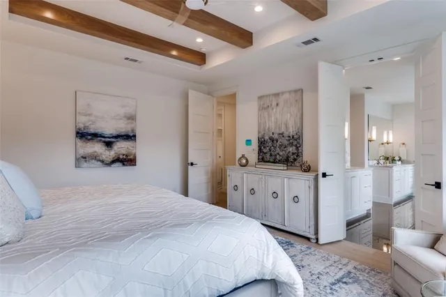 a bedroom with a large bed a chandelier and dresser