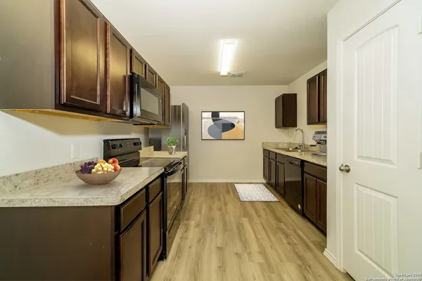 a kitchen with stainless steel appliances a stove top oven a sink a refrigerator and cabinets