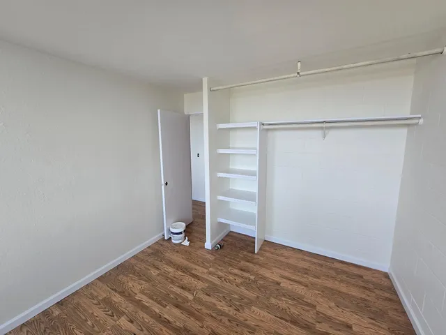 a view of an empty room with wooden floor and closet