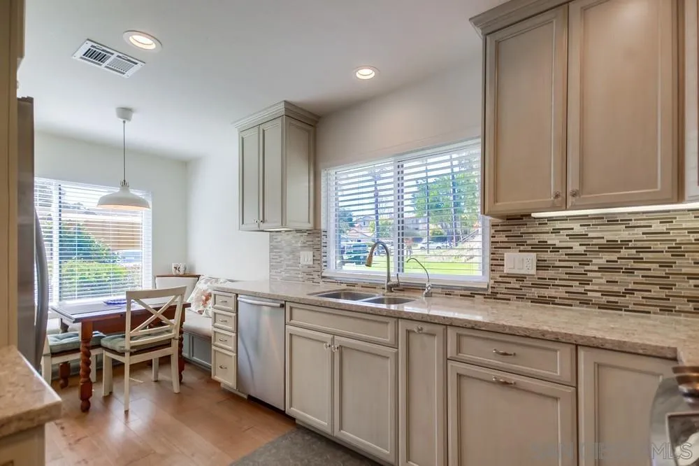 3797 Fallon Circle San Diego, CA 92130 - Photo 12 of 37 a kitchen with a sink white cabinets and wooden floors