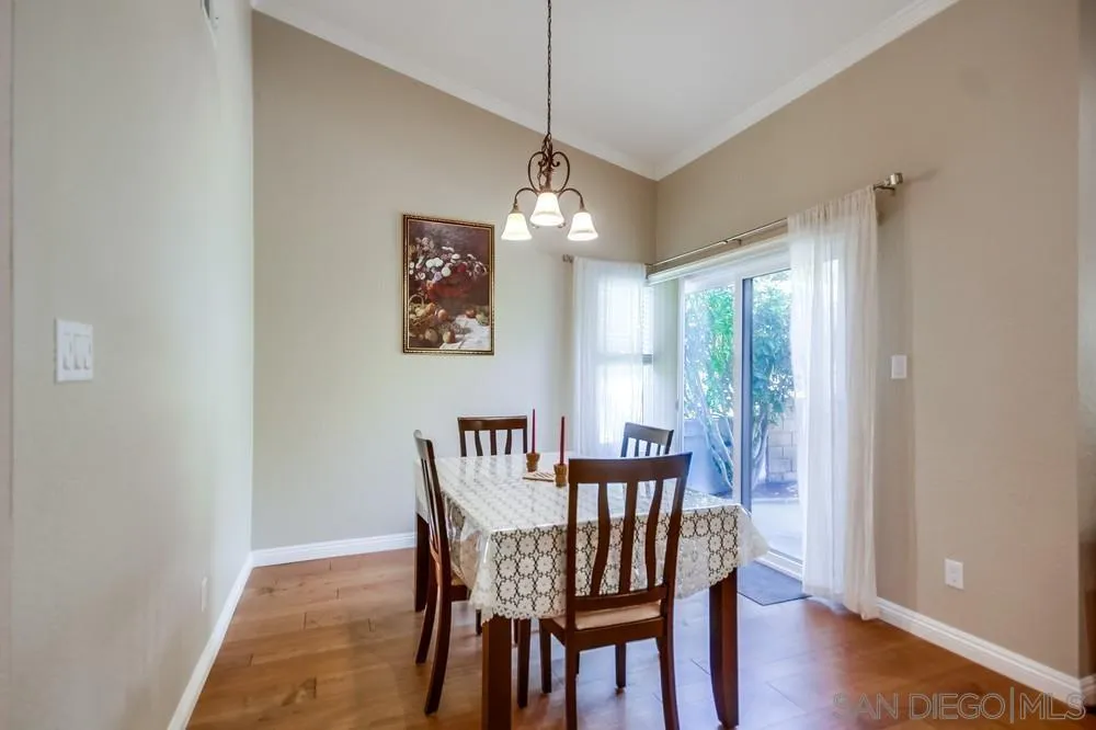 3797 Fallon Circle San Diego, CA 92130 - Photo 8 of 37 a dining room with wooden floor a chandelier a wooden table and chairs